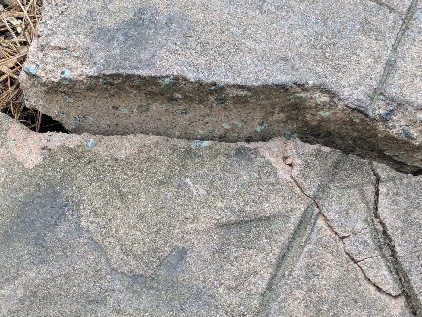 Cracked and heaved concrete slab section broken apart at the joint